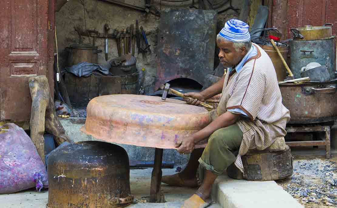 An artisan uses the traditional hammer to create antique impressions on copper