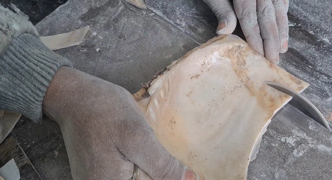 An artisan cuts a mother-of-pearl slab