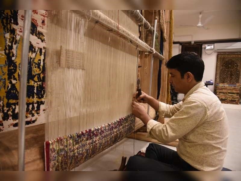 An artisan working on a loom, handmaking a rug