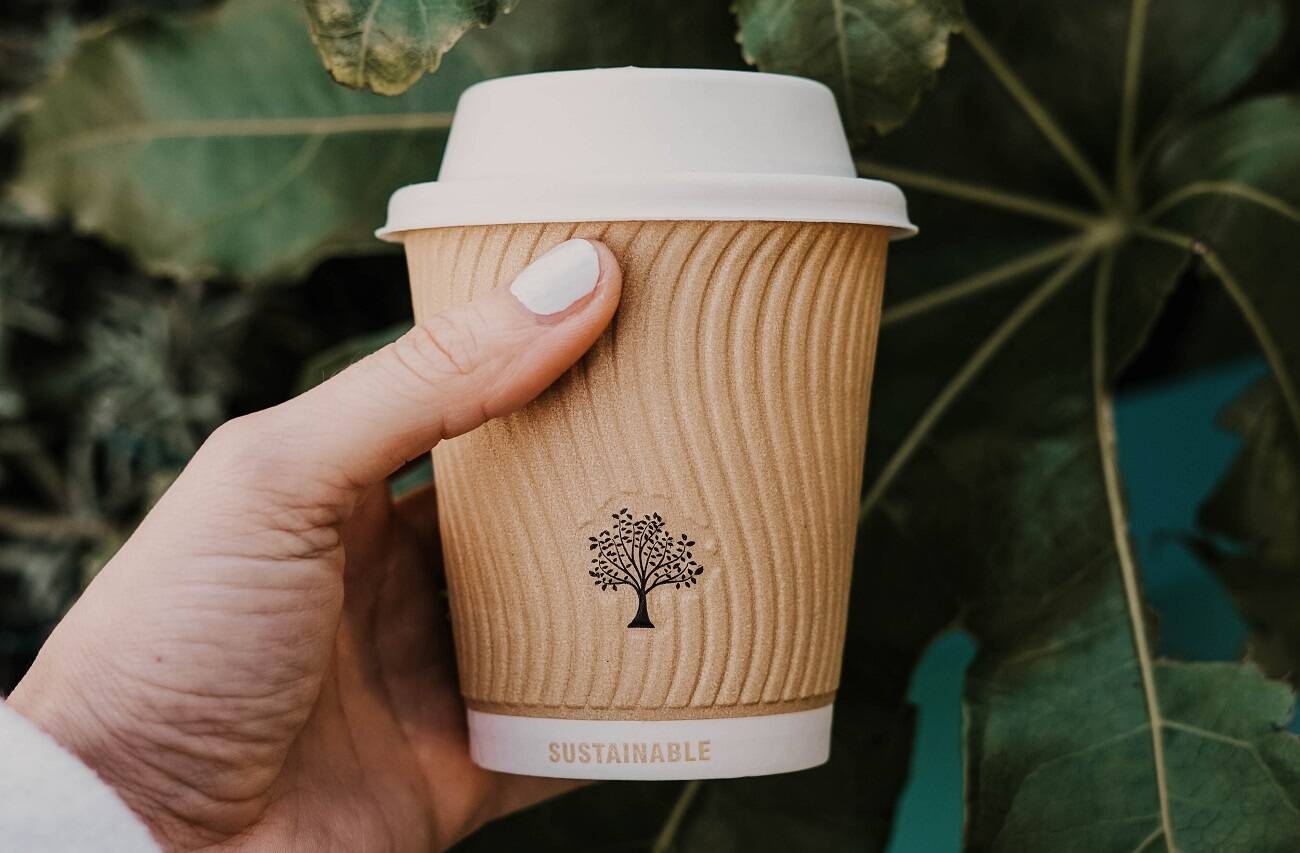 A hand holding a sustainable coffee cup