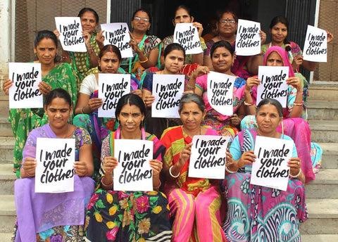 Women artisans holding placard that reads "I made your clothes"