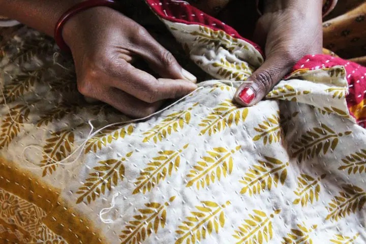 An artisan making kantha embroidery stitch